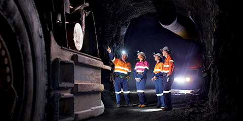 A group of students in a mine shaft underground with mining equipment
