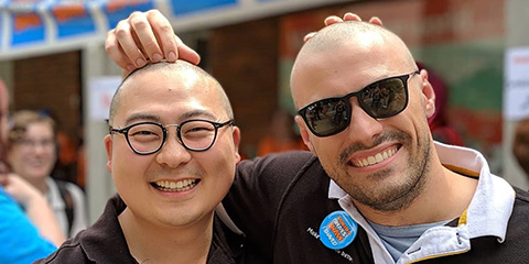 Two male staff members at Curtin University, rubbing each others shaved heads