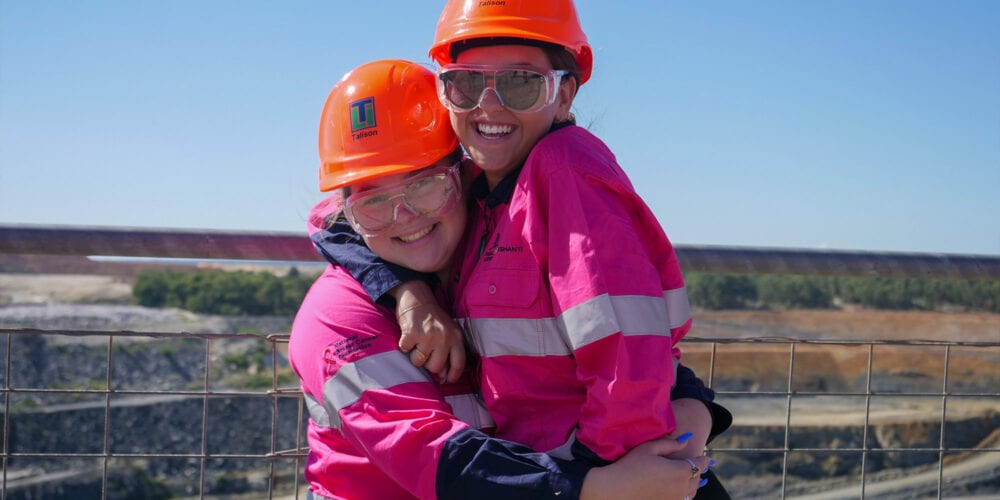 Two young female students smiling in front of a mining super pit