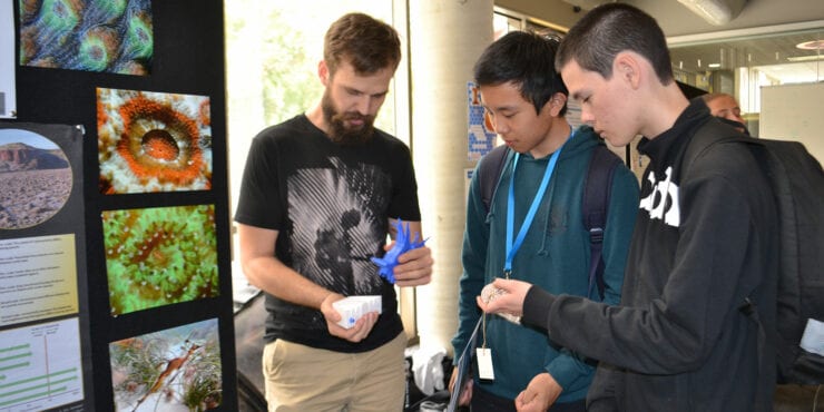 Three students standing in front of a STEM display